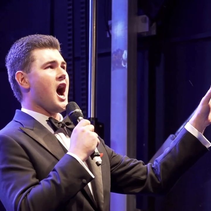 Dylan Forge singing in a tuxedo on stage
