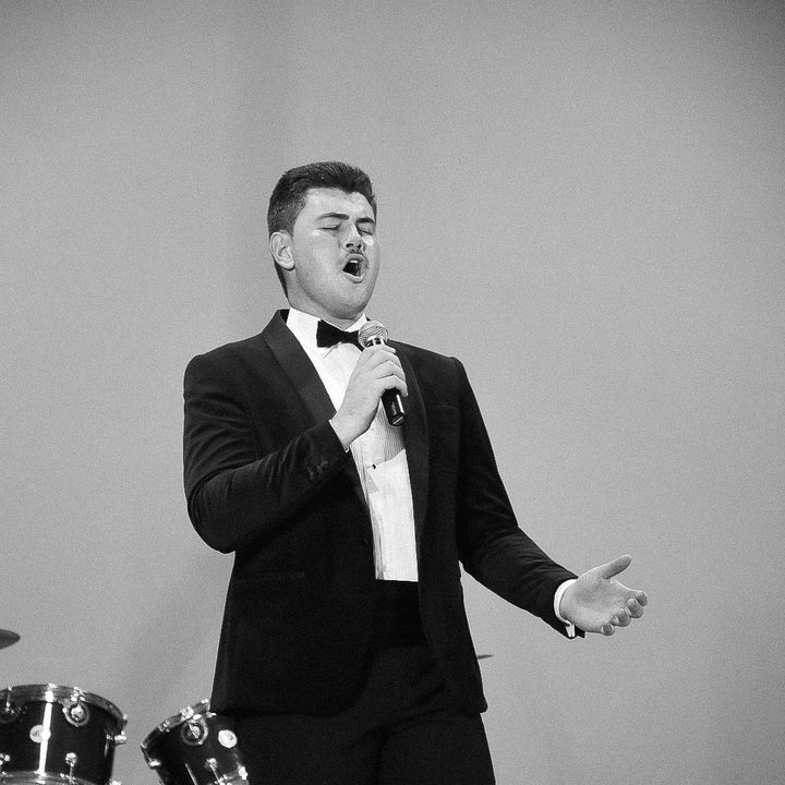 Dylan Forge singing in a tuxedo, black and white
